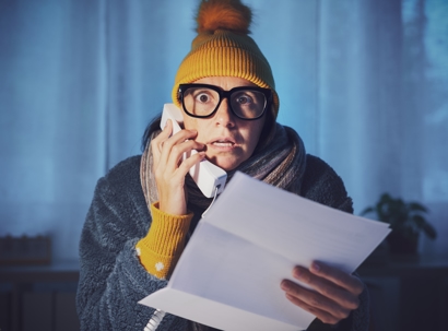 Woman feeling cold at home and checking expensive utility bills