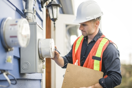 A man with hard hat standing in front of a electric panel